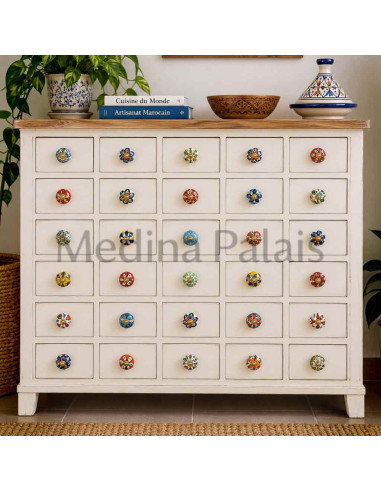 Boutons en céramique multicolores à vis dorées installés sur une commode à tiroirs blanche